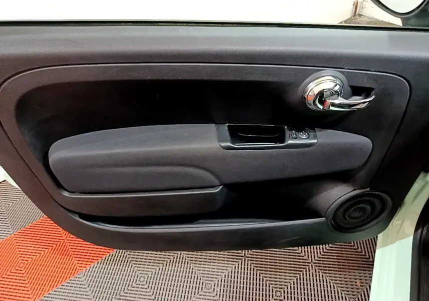 Intérieur de la porte côté conducteur d'une FIAT 500 Lounge 2019 vert, avec poignée chrome et commande vitres.