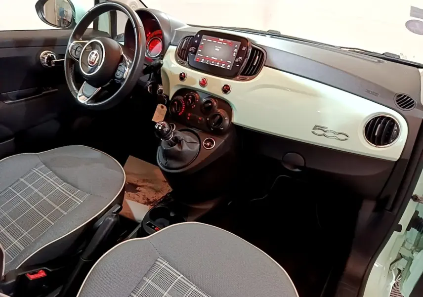 Intérieur avant droit de la Fiat 500 Lounge 2019 avec tableau de bord crème, volant cuir et écran tactile central.