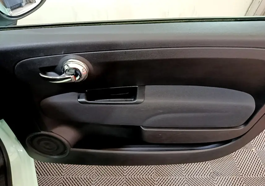 Gros plan sur la porte intérieure côté gauche de la Fiat 500 Lounge 2019 avec poignée chromée et panneau noir.