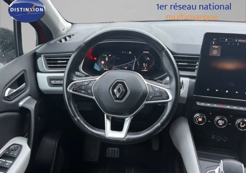 Vue intérieure centrée sur le volant et le tableau de bord numérique du Renault Captur rouge flamme, avec écran tactile.