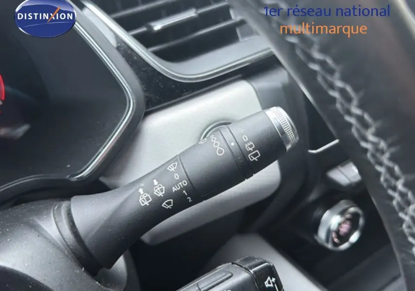 Gros plan sur la commande des essuie-glaces à gauche du volant dans l’habitacle du Renault Captur rouge flamme.