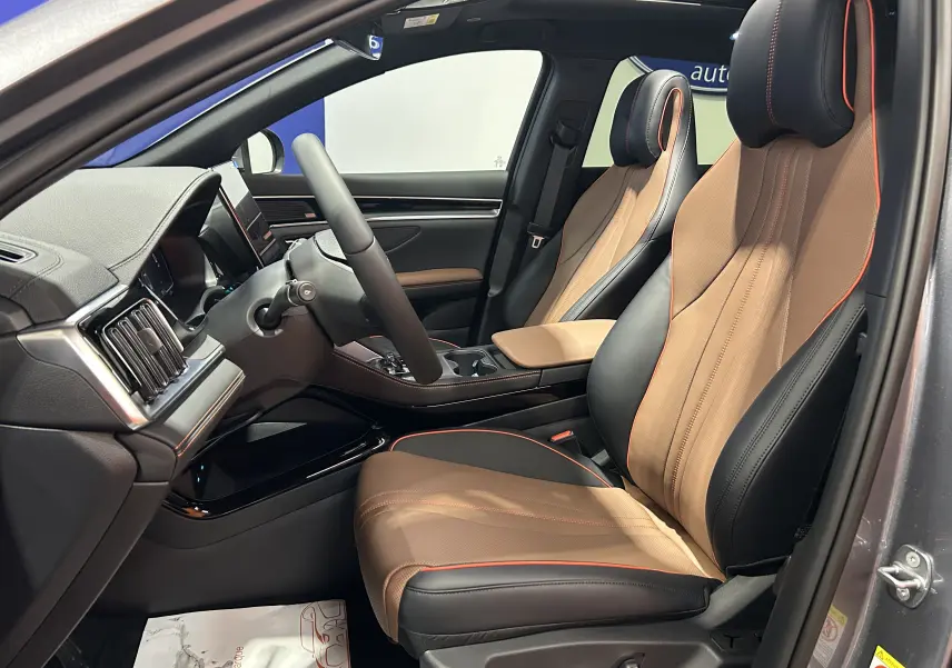 Vue intérieure côté conducteur du BYD SEAL U 2025, sièges cuir marron et noir avec surpiqûres orange, tableau de bord moderne.