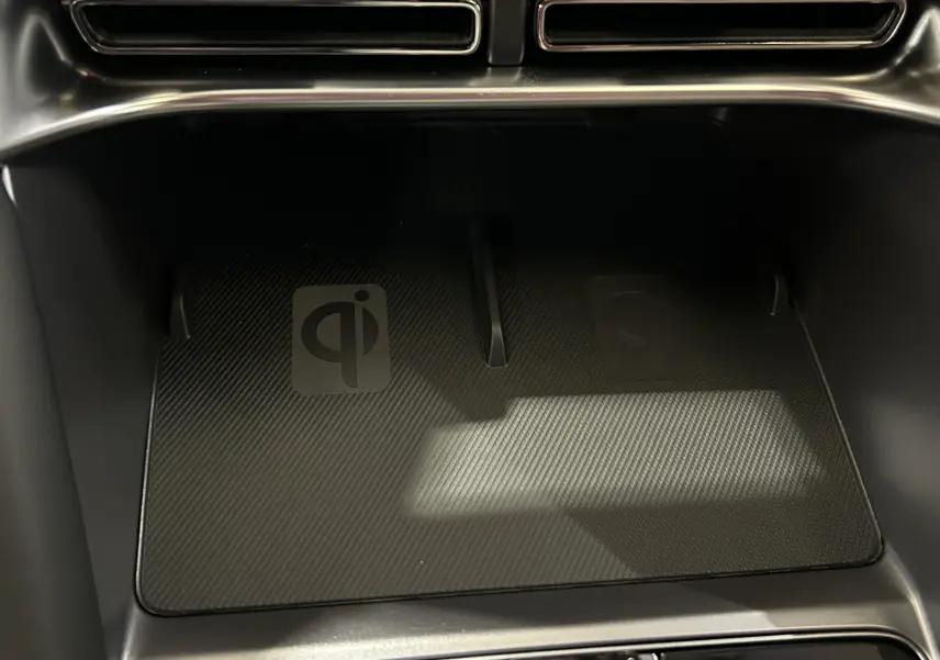 Gros plan sur le chargeur sans fil intérieur noir du BYD SEAL U 2025, avec logo Qi visible sous la console.