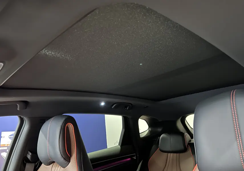 Intérieur du BYD SEAL U vue arrière, sièges cuir marron avec surpiqûres rouges et toit ouvrant panoramique noir.