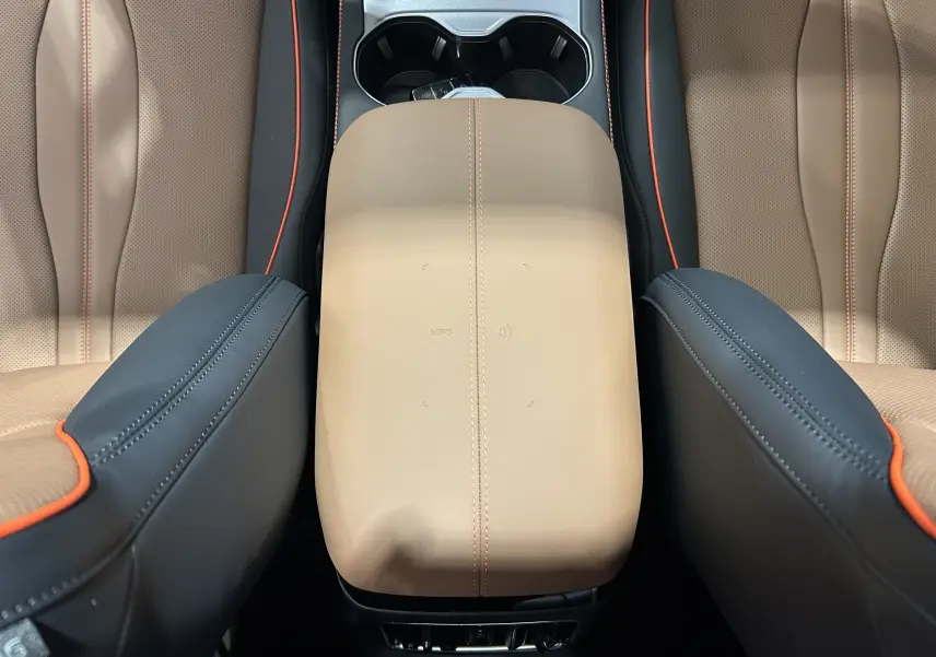 Gros plan sur l'accoudoir central en cuir marron avec surpiqûres orange, entouré des sièges en cuir marron et noir du BYD SEAL U.