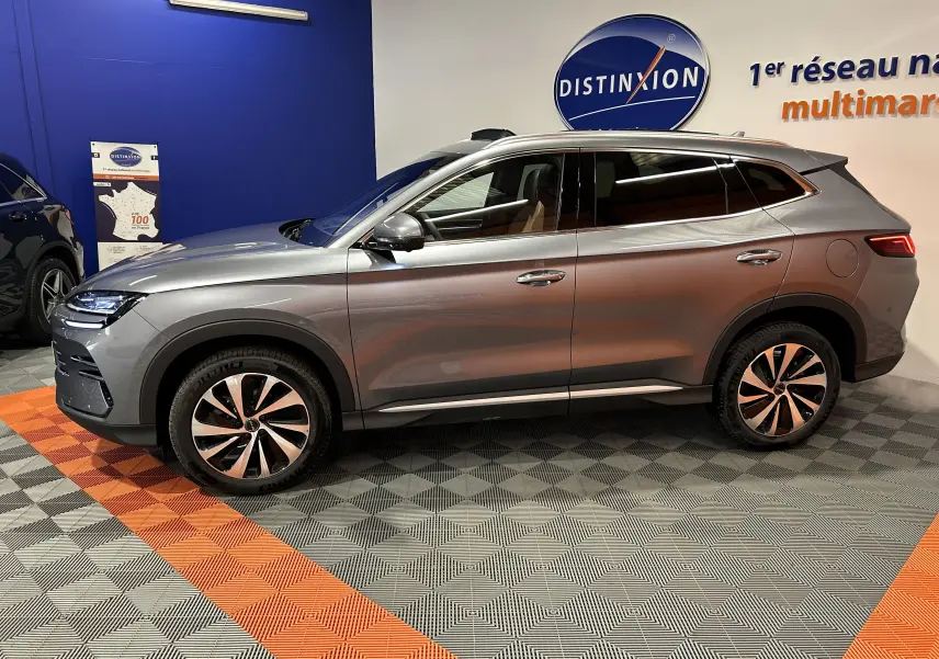 Vue de profil côté gauche d’un BYD SEAL U gris métallisé avec jantes bi-ton et vitres teintées en showroom.