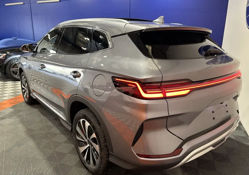 Vue 3/4 arrière droite du SUV BYD SEAL U gris métallisé avec feux arrière LED allumés dans un showroom.