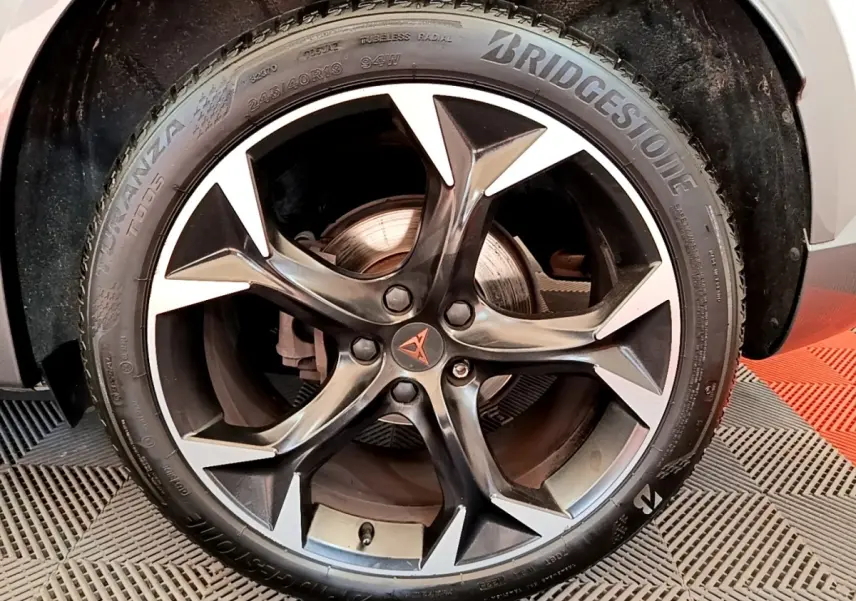 Gros plan sur la jante alliage noire et argentée avec logo CUPRA au centre, montée sur pneu Bridgestone.