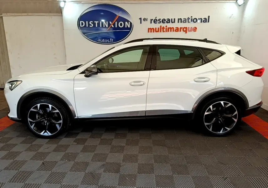 Profil droit d'un CUPRA Formentor blanc 2023 avec jantes noires et toit ouvrant, en intérieur showroom.