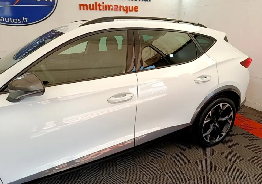 Vue latérale droite du CUPRA Formentor blanc avec jantes noires et rétroviseurs gris dans un showroom.