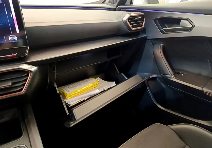 Intérieur noir et beige du CUPRA Formentor 2023, vue côté passager avec boîte à gants ouverte et éclairage d'ambiance violet.