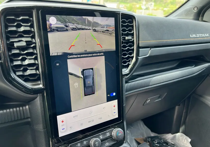 Vue intérieure centrée sur l’écran tactile vertical du Ford Ranger Wildtrak X blanc glacier avec tableau de bord noir et surpiqûres jaunes.