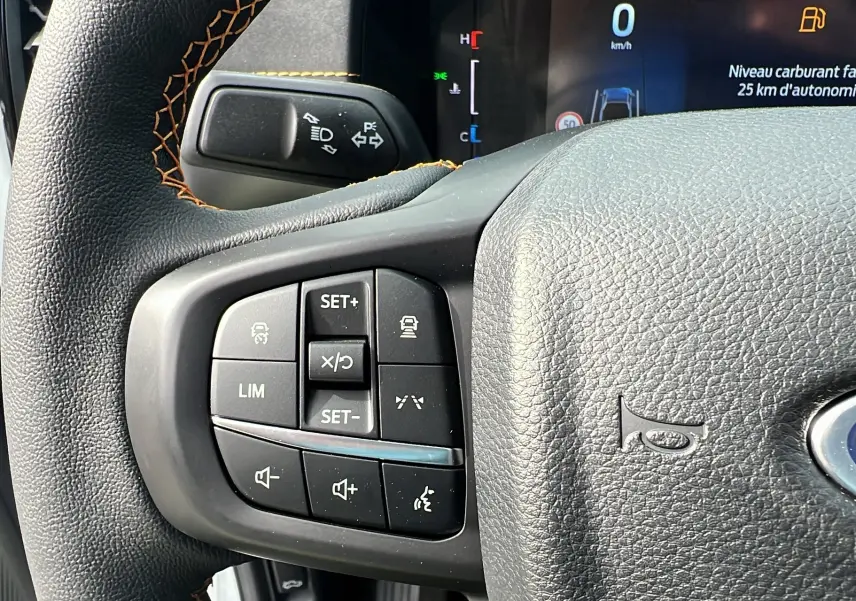 Gros plan sur le volant cuir multifonctions du Ford Ranger blanc glacier avec commandes de régulateur et écran digital en arrière-plan.