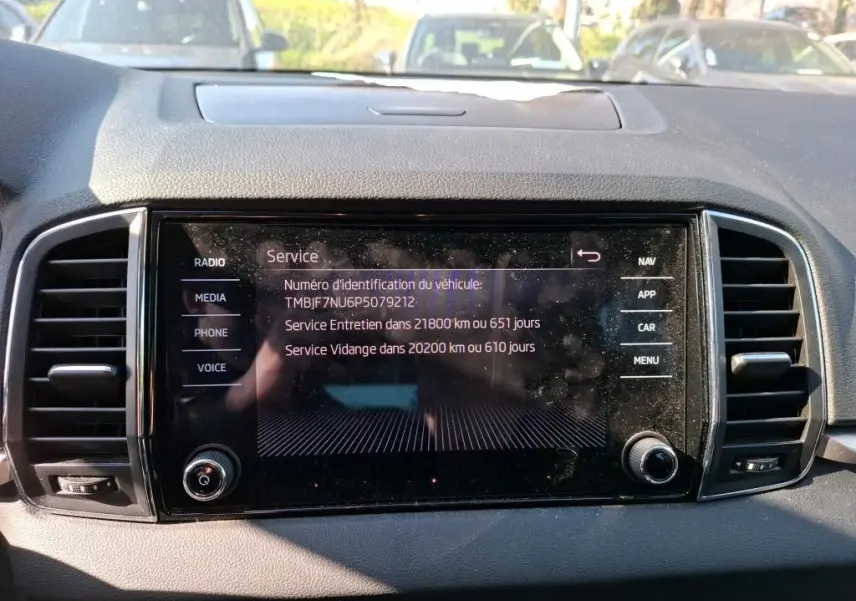 Écran tactile central du tableau de bord d'une Skoda Karoq 2.0 TDI gris, affichant les informations de service.
