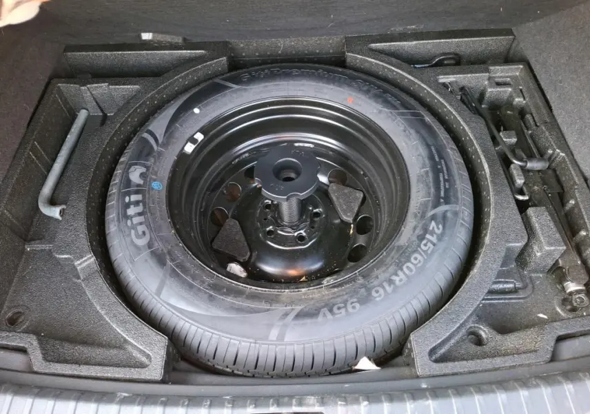 Gros plan sur la roue de secours et les outils de bord du coffre d'un Skoda Karoq gris 2023.
