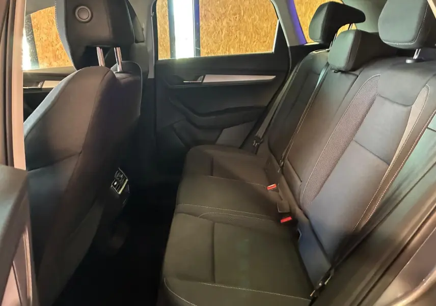 Vue intérieure côté droit des sièges arrière noirs du Skoda Karoq 2023 avec finitions tissu et ceintures visibles.