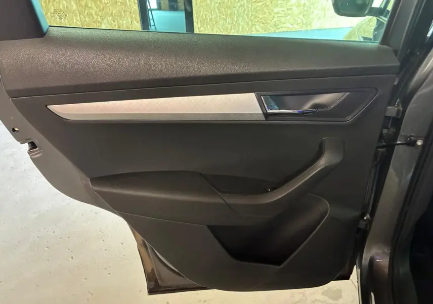 Porte arrière droite gris foncé de Skoda Karoq 2023 avec insert décoratif argenté et poignée chromée.