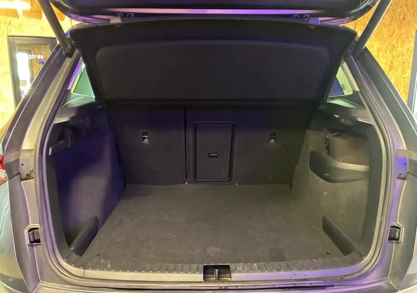 Coffre ouvert vu de l'arrière d'un Skoda Karoq gris 2023, espace de chargement vide et tapis noir.