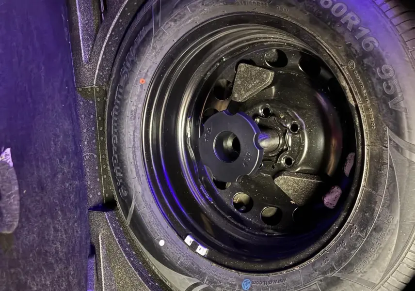 Gros plan sur la roue de secours noire dans le coffre d’un Skoda Karoq gris, vue de dessus.
