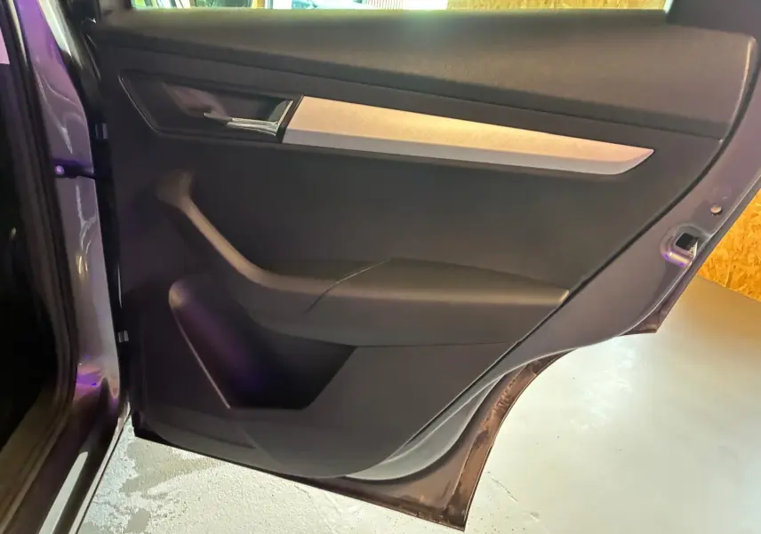 Vue intérieure de la porte arrière gauche gris foncé du Skoda Karoq 2023 avec poignée argentée et rangement intégré.