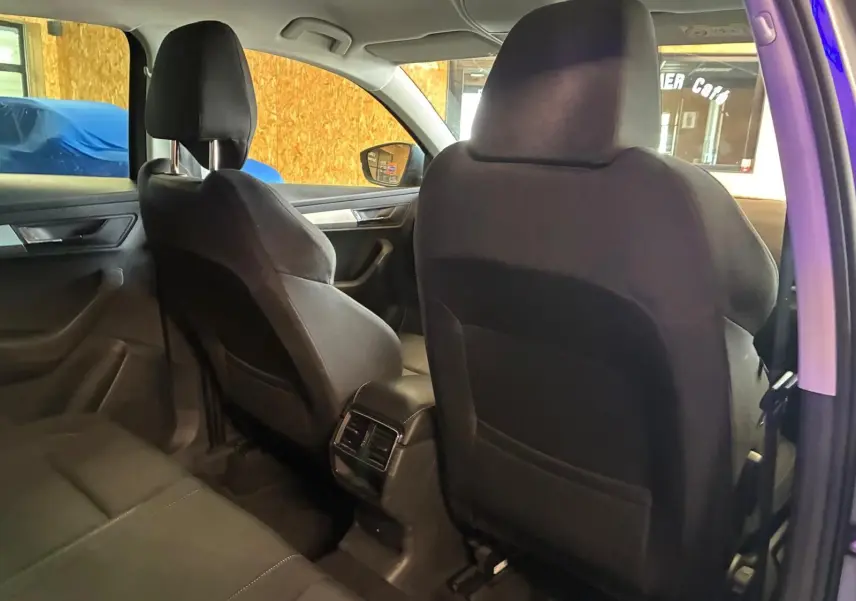 Vue intérieure arrière droite du Skoda Karoq gris 2023, montrant les sièges avant noirs et les aérateurs centraux.