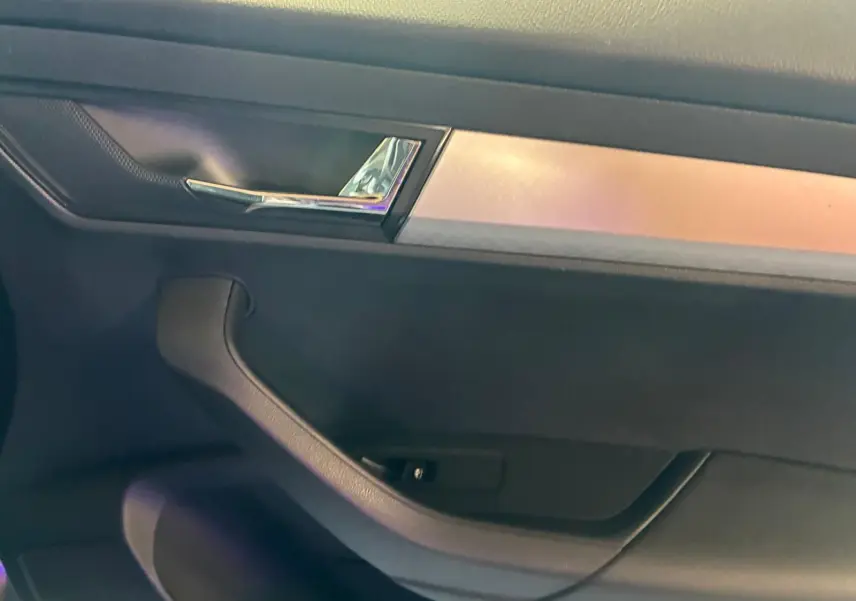 Détail de la poignée intérieure et garniture noire avec insert chromé d'une porte côté gauche d'un Skoda Karoq gris.