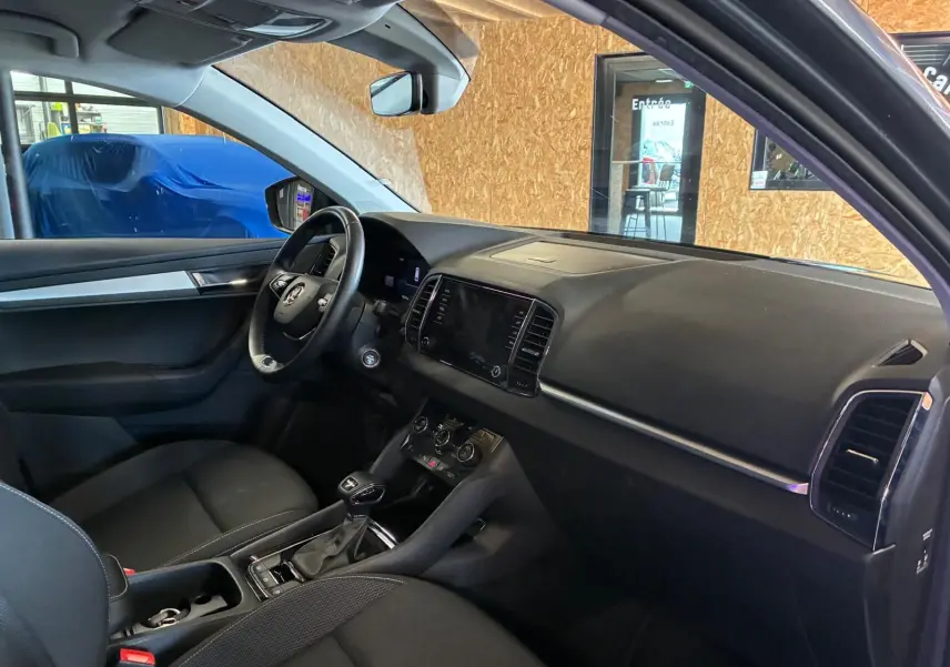 Vue intérieure côté conducteur du Skoda Karoq gris 2023, avec tableau de bord noir et volant multifonctions.