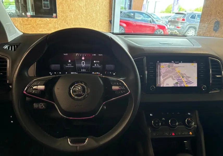 Vue intérieure centrée sur le volant cuir multifonctions et l’écran tactile du tableau de bord du Skoda Karoq gris 2023.
