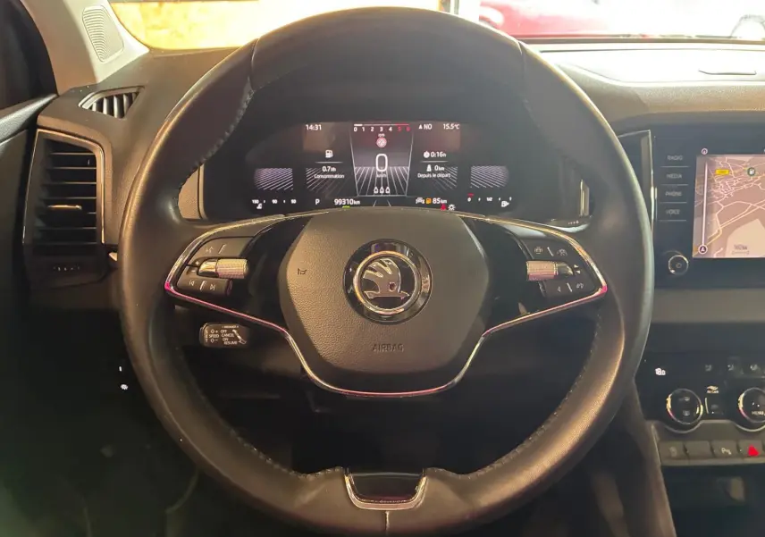 Vue rapprochée du volant cuir multifonctions de la Skoda Karoq gris avec tableau de bord numérique et écran tactile.