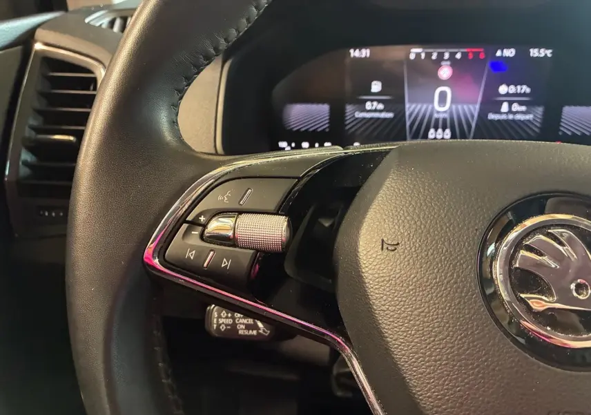 Gros plan sur le volant cuir multifonctions noir du Skoda Karoq 2023 avec tableau de bord digital en arrière-plan.
