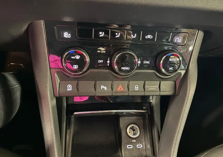 Gros plan sur la console centrale du Skoda Karoq 2023, avec commandes climatisation et ports USB-C visibles.