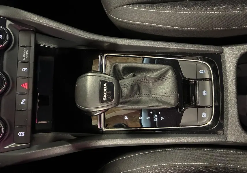 Vue rapprochée du levier de vitesses automatique noir marqué SKODA dans la console centrale du Skoda Karoq gris.