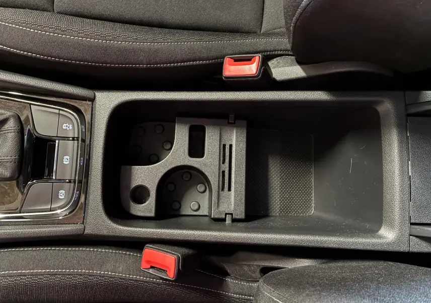 Vue plongeante sur la console centrale noire du Skoda Karoq 2023 avec porte-gobelets et frein à main électrique.