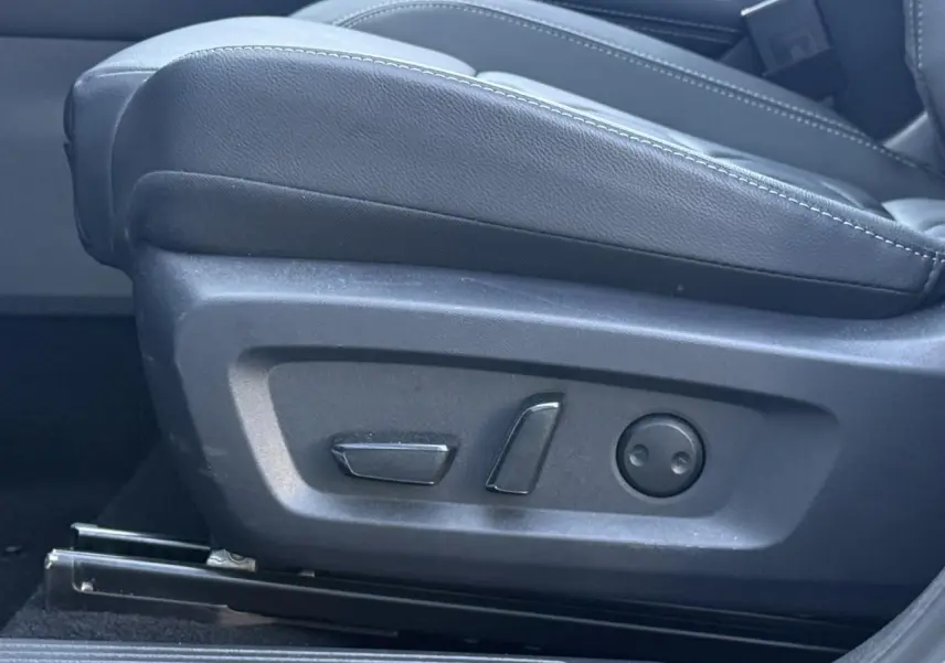 Détail des commandes électriques du siège avant droit en cuir noir du Nissan Qashqai blanc nacré 2025.