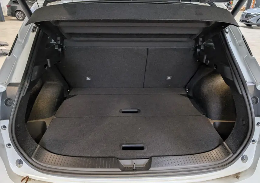 Coffre ouvert du Nissan Qashqai blanc nacré 2025, montrant un espace de chargement plat et bien fini.