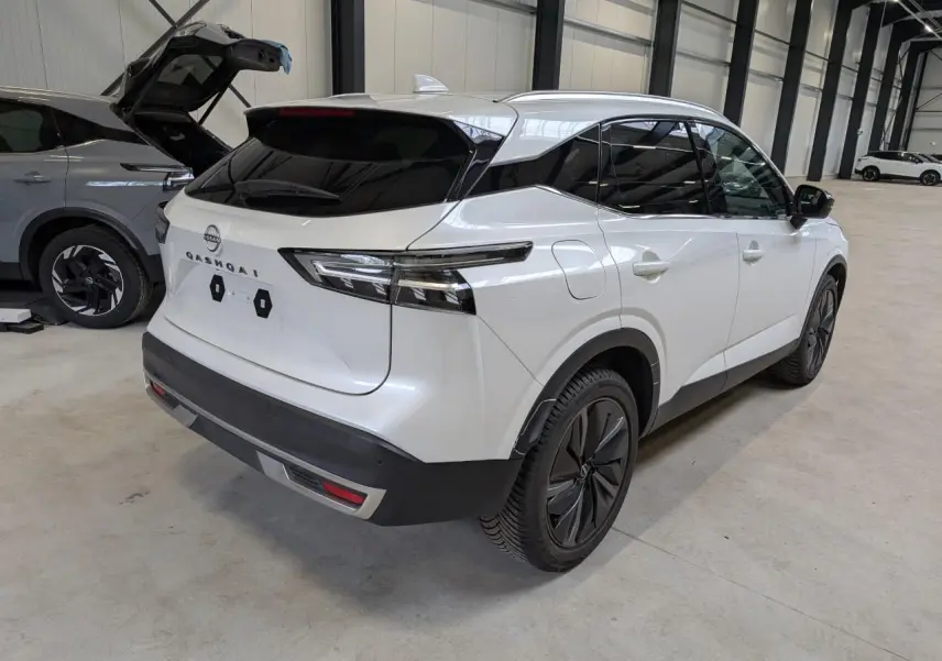 Vue 3/4 arrière droite du Nissan Qashqai blanc nacré avec toit noir et jantes alliage 19 pouces dans un garage.