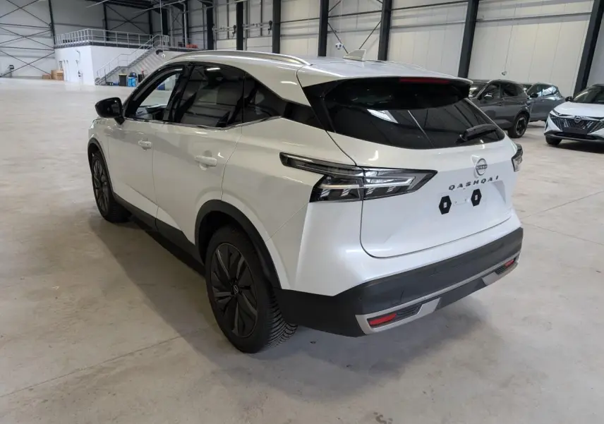 Vue 3/4 arrière droite du Nissan Qashqai blanc nacré 2025 avec toit panoramique et jantes alliage noires.