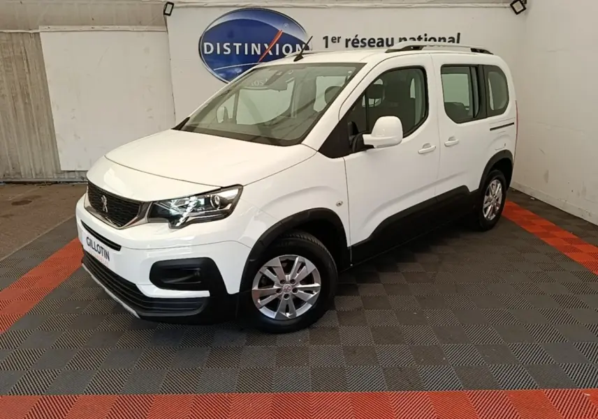 Peugeot Rifter blanc en 3/4 avant droit, avec jantes alliage et protections noires sur bas de caisse.