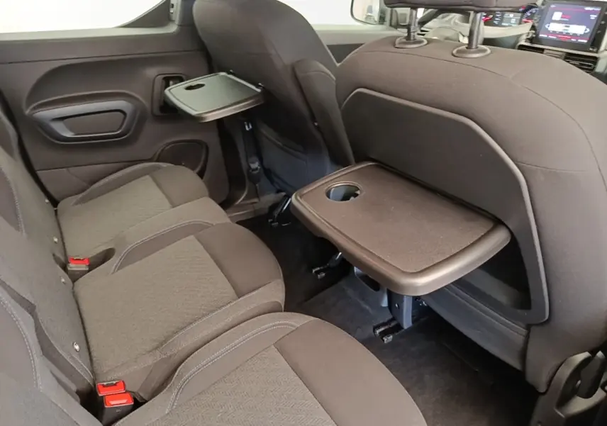 Vue intérieure arrière du Peugeot Rifter 2020 avec banquette 3 places noire et tablettes rabattables sur les dossiers avant.