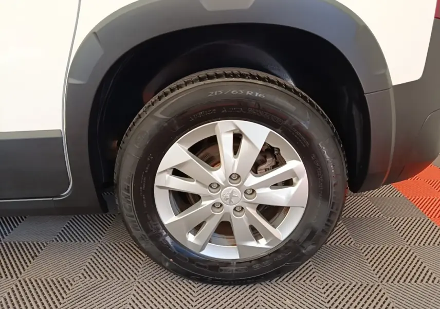 Gros plan sur la roue avant droite d’un Peugeot Rifter blanc, avec jante alliage et pneu Michelin visible.