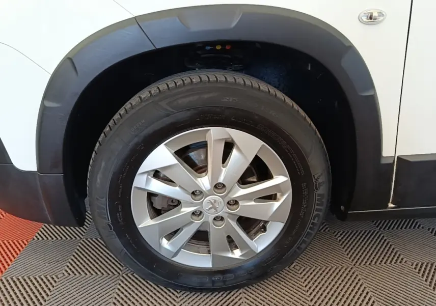 Gros plan sur la roue avant gauche du Peugeot Rifter blanc, avec jante alliage et pneu Michelin visible.