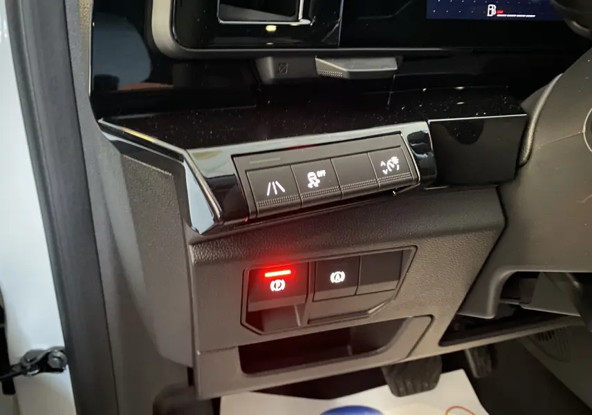 Boutons de commande du frein à main électronique et aides à la conduite sur la gauche du tableau de bord d'un Renault Austral blanc nacré 2023.