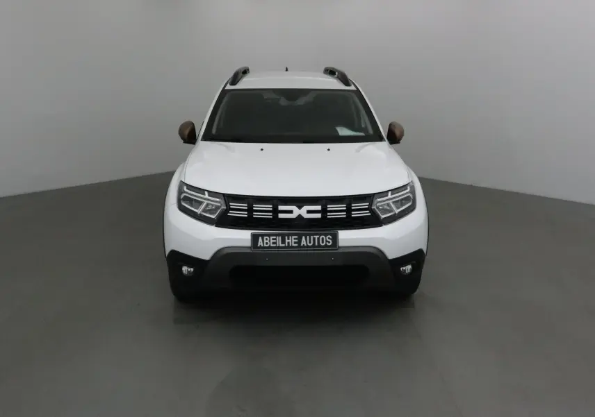 Vue frontale d'un Dacia Duster blanc 2024 avec calandre noire et rétroviseurs couleur bronze.