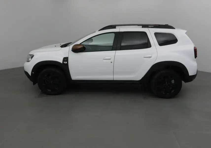 Profil côté gauche d'un Dacia Duster blanc 2024 avec coques de rétroviseurs bronze et jantes noires.