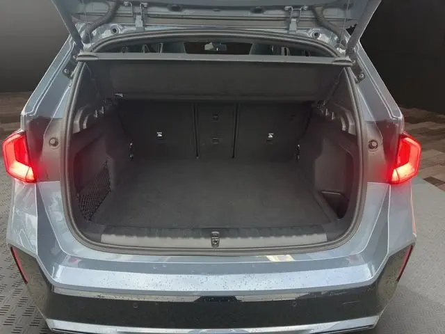 Vue arrière ouverte du coffre d'un BMW X1 Storm Bay 2024, avec feux arrière allumés et intérieur spacieux noir.