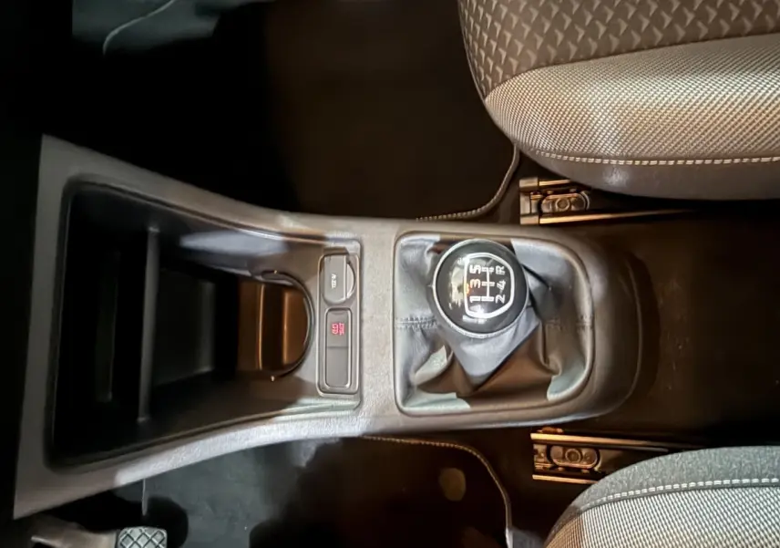 Vue plongeante sur la console centrale du Volkswagen Up 1.0 65 Active 2022, avec levier de vitesse manuel et sièges tissu gris.