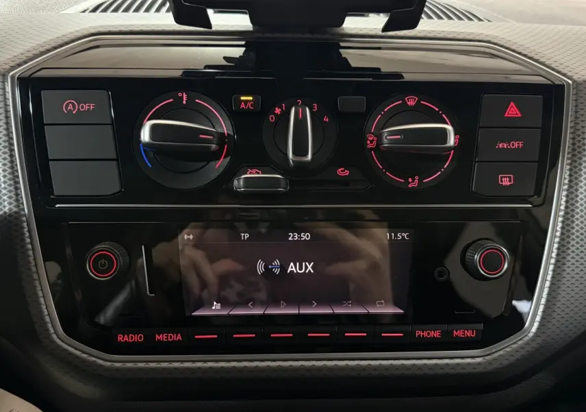 Vue rapprochée du tableau de bord noir brillant de la Volkswagen Up 1.0 65 Active avec commandes climatisation et écran multifonction.