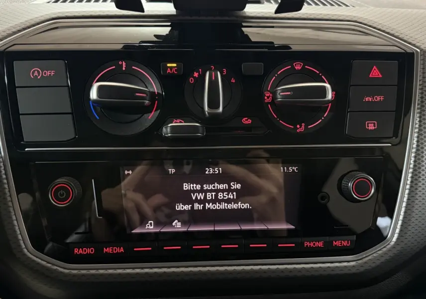 Tableau de bord noir du Volkswagen Up 1.0 65 Active 2022 avec commandes climatisation et écran central allumé.