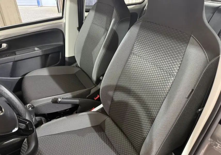 Vue rapprochée des sièges avant gris foncé et de la console centrale d'une Volkswagen Up 1.0 65 Active 2022.