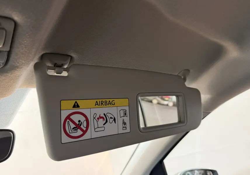 Détail du pare-soleil côté conducteur gris clair avec miroir et avertissement airbag dans un Volkswagen Up 2022.